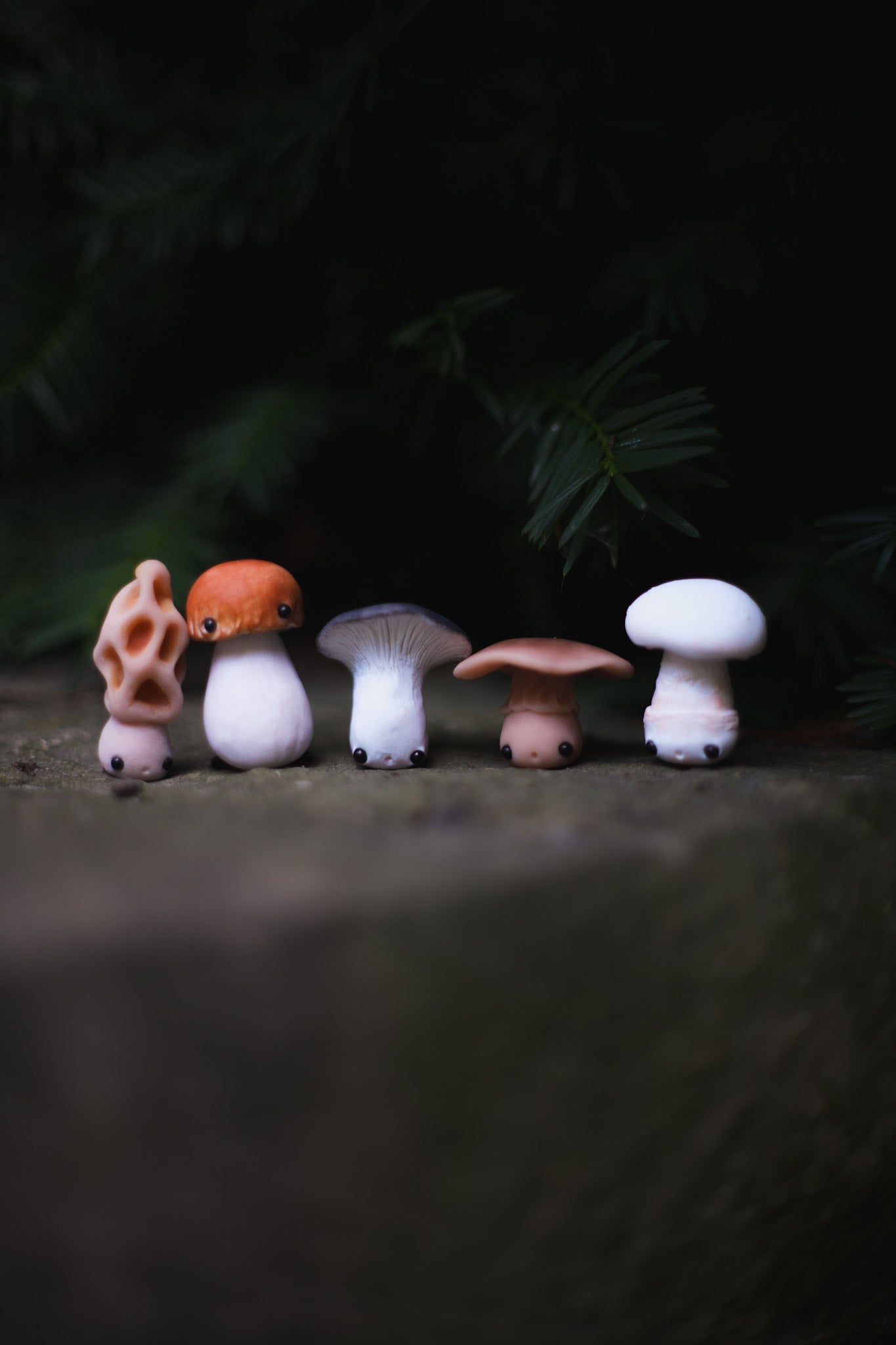 Set of small mushroom figurines on a dark surface with a blurred natural background