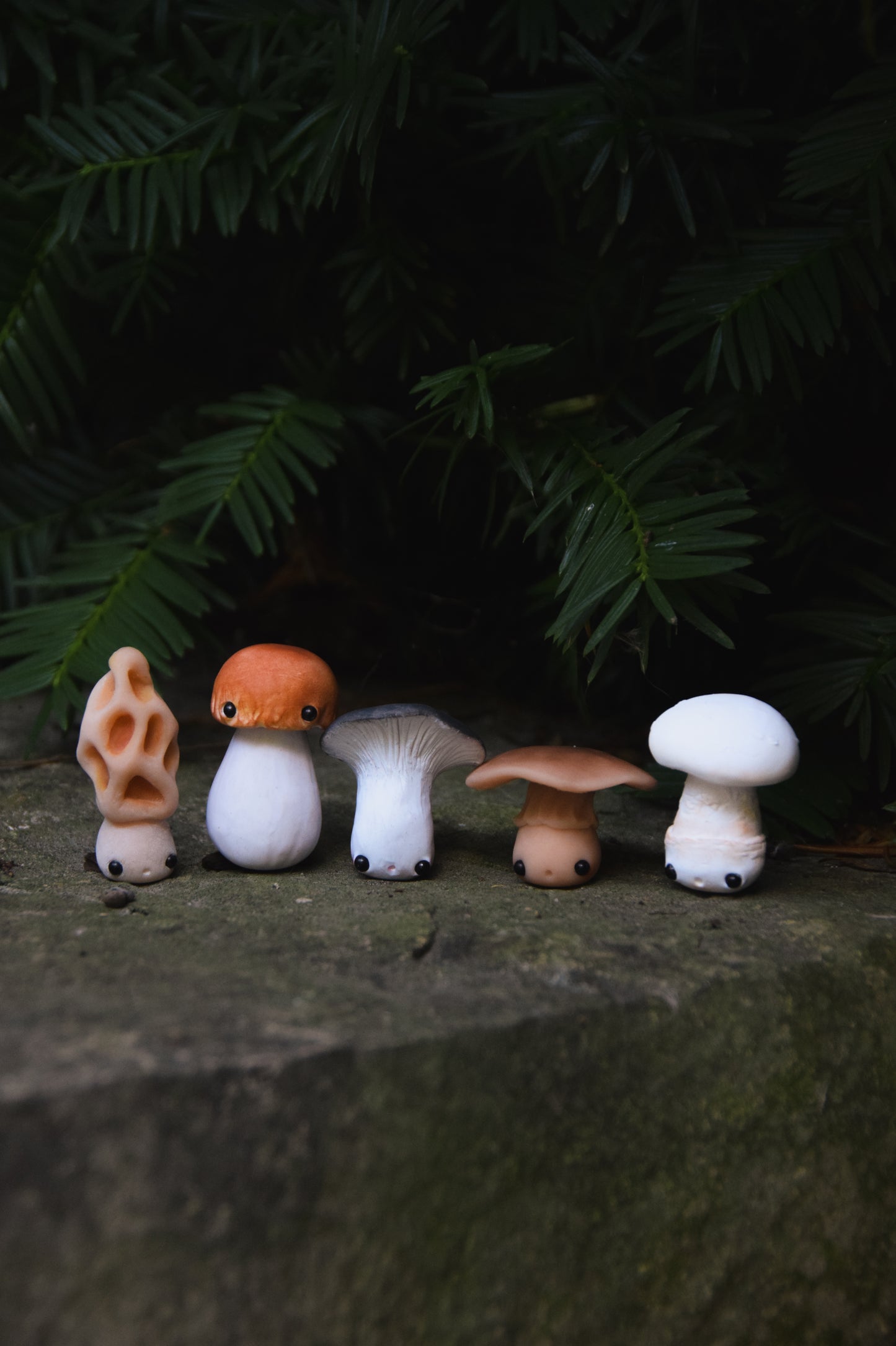 Set of small mushroom figurines on a stone surface with a dark background